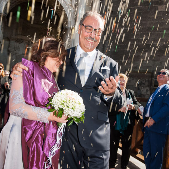 Matrimoni, sposi accolti da una pioggia di riso illuminato dal sole di taglio all'uscita del municipio