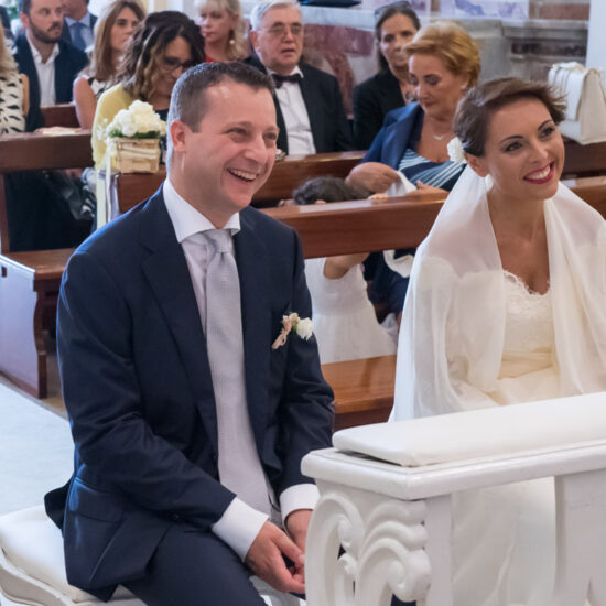 Matrimoni, sposi seduti in chiesa che sorridono avanti a loro