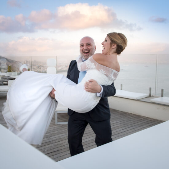 Matrimoni, lo sposo prende la sposa in braccio su un terrazzo panoramico