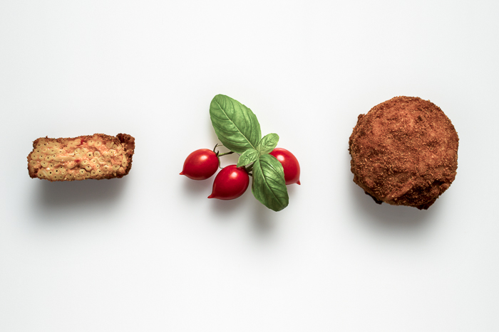 Giusva servizi fotografici - cataloghi still life, frittatina di maccheroni sia intera che tagliata con tre pomodorini e foglie di basilico al centro, tutto visto dall'alto.