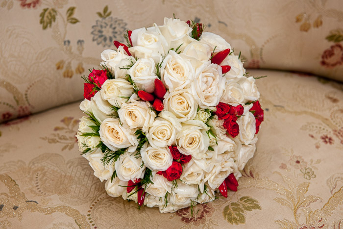 Giusva servizi fotografici - matrimoni, bouquet sferico composto di rose bianche con boccioli di roselline rosse, appoggiato sul divano ricamato